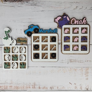 May include: Three wooden game boards with different themes. The first board features a dinosaur with the name Jaxon, the second board features a truck with the name Marshall, and the third board features a unicorn with the name Onah.