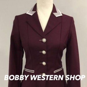 May include: A burgundy riding jacket with a white collar and white piping on the pockets. The jacket has five pearl-like buttons down the front. The text "BOBBY WESTERN SHOP" is visible at the bottom of the image.