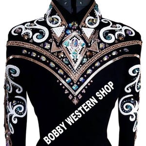 May include: A black long-sleeve shirt featuring intricate white scrollwork embroidery, metallic bronze trim, and numerous iridescent crystals arranged in geometric patterns across the chest and sleeves, with the text BOBBY WESTERN SHOP.
