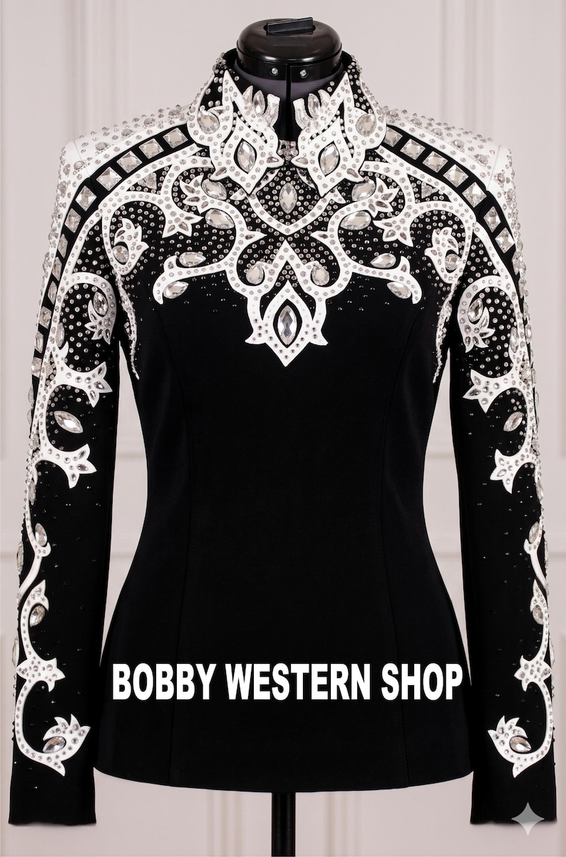 May include: Black equestrian show jacket with white and silver embellishments. The jacket features intricate designs with rhinestones and a high collar. The text "BOBBY WESTERN SHOP" is displayed across the bottom.