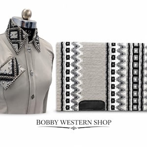 May include: A light beige long-sleeve shirt with a high collar and cuffs featuring black and clear crystal embellishments, paired with a rectangular saddle pad in shades of grey, black, and white with a geometric pattern and black leather patch.