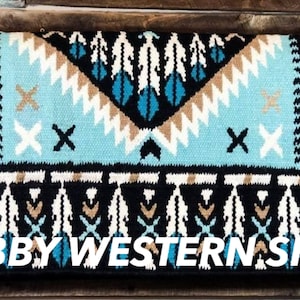 May include: A turquoise, black, white, and brown saddle blanket with a geometric pattern. The blanket has a fringe border and the text "BOBBY WESTERN SHOP" is printed on the bottom.