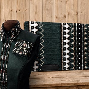 Könnte beinhalten: Ein dunkelgrünes Reitturniershirt mit hohem Kragen und Manschetten, die mit Metallnieten und Kristallen verziert sind, dazu eine passende rechteckige Satteldecke mit geometrischem Muster in Dunkelgrün, Schwarz, Weiß und Beige.