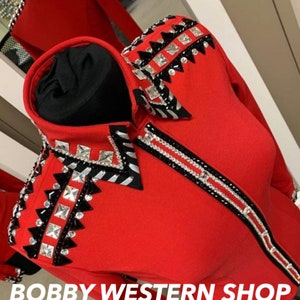 May include: Red long-sleeve shirt with black and white trim and rhinestones. The shirt has a geometric pattern on the shoulders and a black collar. The text "BOBBY WESTERN SHOP" is at the bottom of the image.