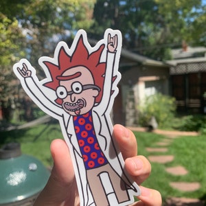 May include: A sticker of a cartoon character with red hair, wearing a white lab coat and a red and blue shirt with a donut pattern. The character is raising both hands in the air with the index and pinky fingers extended, making the rock and roll hand gesture.