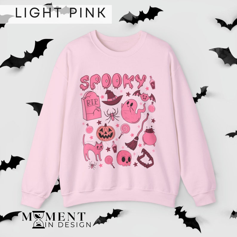 pink aesthetic halloween sweatshirt for women. contains pink graphics of ghosts, pumpkins, cats, potions, and candy.