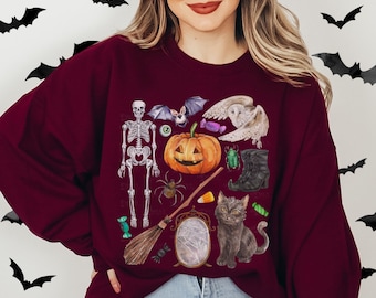 May include: Maroon sweatshirt featuring a Halloween-themed design. The graphic includes a skeleton, pumpkin, bat, owl, spider, cat, broom, and other spooky elements. The word "MAROON" is printed at the top left.