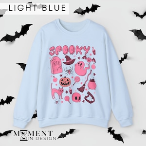 pink aesthetic halloween sweatshirt for women. contains pink graphics of ghosts, pumpkins, cats, potions, and candy.