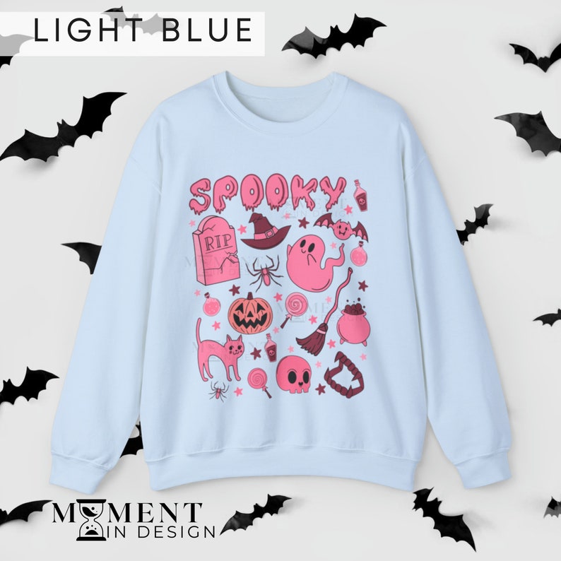 pink aesthetic halloween sweatshirt for women. contains pink graphics of ghosts, pumpkins, cats, potions, and candy.