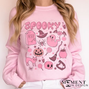 pink aesthetic halloween sweatshirt for women. contains pink graphics of ghosts, pumpkins, cats, potions, and candy.