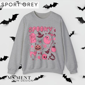 pink aesthetic halloween sweatshirt for women. contains pink graphics of ghosts, pumpkins, cats, potions, and candy.