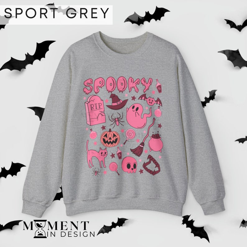 pink aesthetic halloween sweatshirt for women. contains pink graphics of ghosts, pumpkins, cats, potions, and candy.
