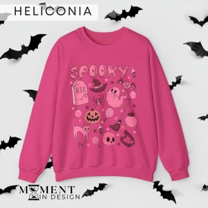 pink aesthetic halloween sweatshirt for women. contains pink graphics of ghosts, pumpkins, cats, potions, and candy.