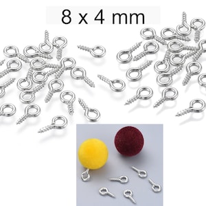 Può includere: Primo piano di un mucchio di ganci a occhiello a vite in argento, ognuno con un anello di 8 mm di diametro e una vite da 4 mm. L'immagine mostra anche due piccole sfere, una gialla e una rossa, con ganci a occhiello a vite attaccati.