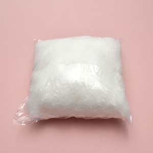 May include: A white, fluffy material packaged in a clear plastic bag. The bag is sealed and the material is visible through the plastic.