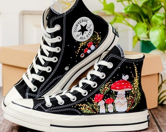 May include: A pair of black high-top Converse sneakers with white soles. The sneakers are decorated with embroidered mushrooms and greenery.