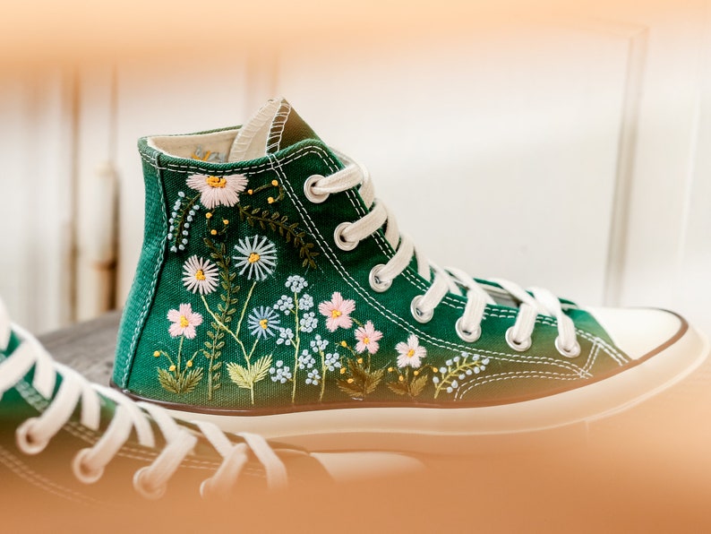 Puede incluir: Zapatillas altas verdes con cordones blancos y puntera blanca. Las zapatillas est&aacute;n adornadas con flores bordadas en tonos rosas, blancos y azules, con hojas verdes y detalles amarillos. El dise&ntilde;o floral est&aacute; en el lateral del zapato.