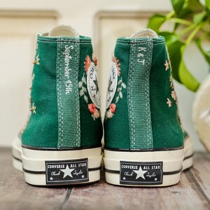 May include: A pair of green high-top Converse sneakers with white soles and black stitching. The sneakers are embroidered with flowers and have the text "September 15th" and "K&J" on the back.