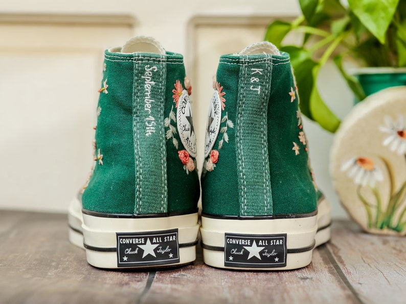 May include: A pair of green high-top Converse sneakers with white soles and black stitching. The sneakers are embroidered with flowers and have the text "September 15th" and "K&J" on the back.