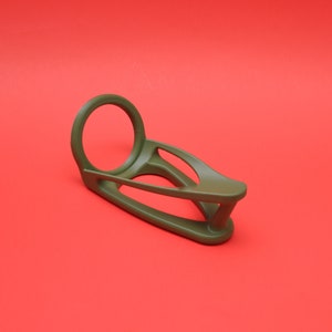 K&ouml;nnte beinhalten: Ein gr&uuml;ner Plastik-Ringhalter mit einer runden &Ouml;ffnung und einem geschwungenen Design. Der Halter ist so konzipiert, dass er einen Ring sicher h&auml;lt.