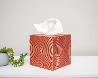 May include: A copper-colored tissue box cover with a woodgrain pattern. The cover is square and has a raised design.