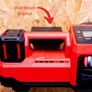 May include: A red and black power tool with a handle, mounted on a wall. The tool has a digital display and a black battery compartment. The text "Wall Mount Bracket" is above the tool.
