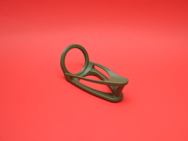 K&ouml;nnte beinhalten: Ein gr&uuml;ner Plastik-Ringhalter mit einer runden &Ouml;ffnung und einem geschwungenen Design. Der Halter ist so konzipiert, dass er einen Ring sicher h&auml;lt.