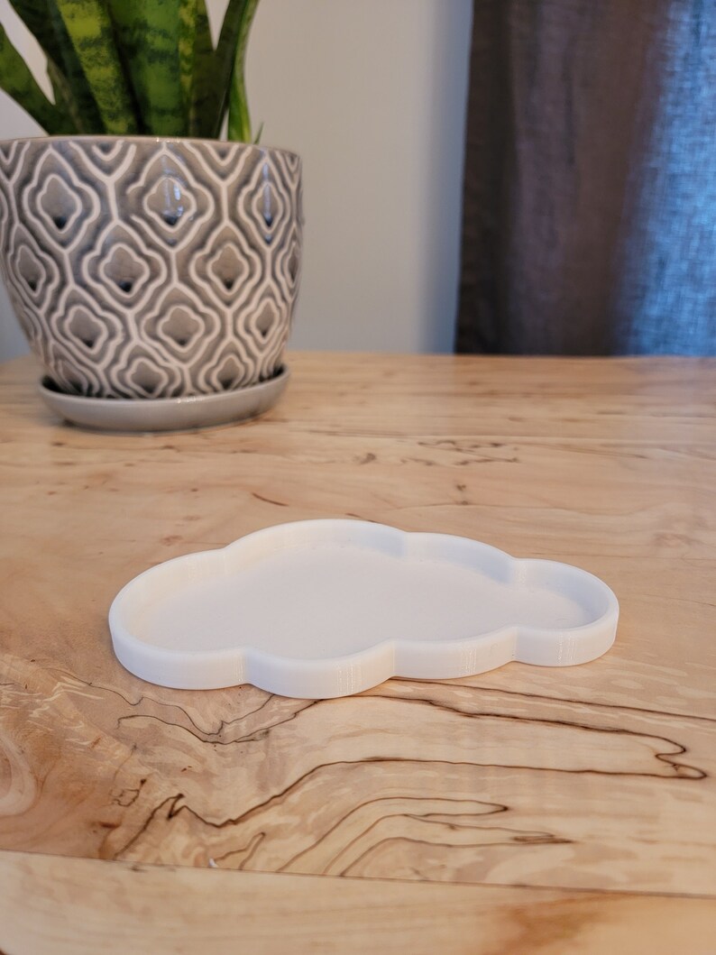 May include: A white cloud-shaped dish made of ceramic. The dish is sitting on a wooden surface.