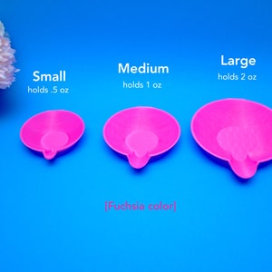 May include: Three fuchsia-colored, small, medium, and large, round trays with a small handle. The small tray holds 0.5 oz, the medium holds 1 oz, and the large holds 2 oz. The text reads "Small holds .5 oz", "Medium holds 1 oz", and "Large holds 2 oz".