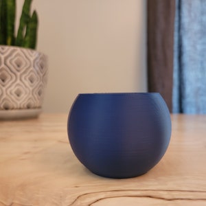 May include: A small, round, blue planter pot made of ceramic.