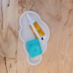 May include: A white cloud-shaped tray with a yellow tube of toothpaste and a blue floss container.