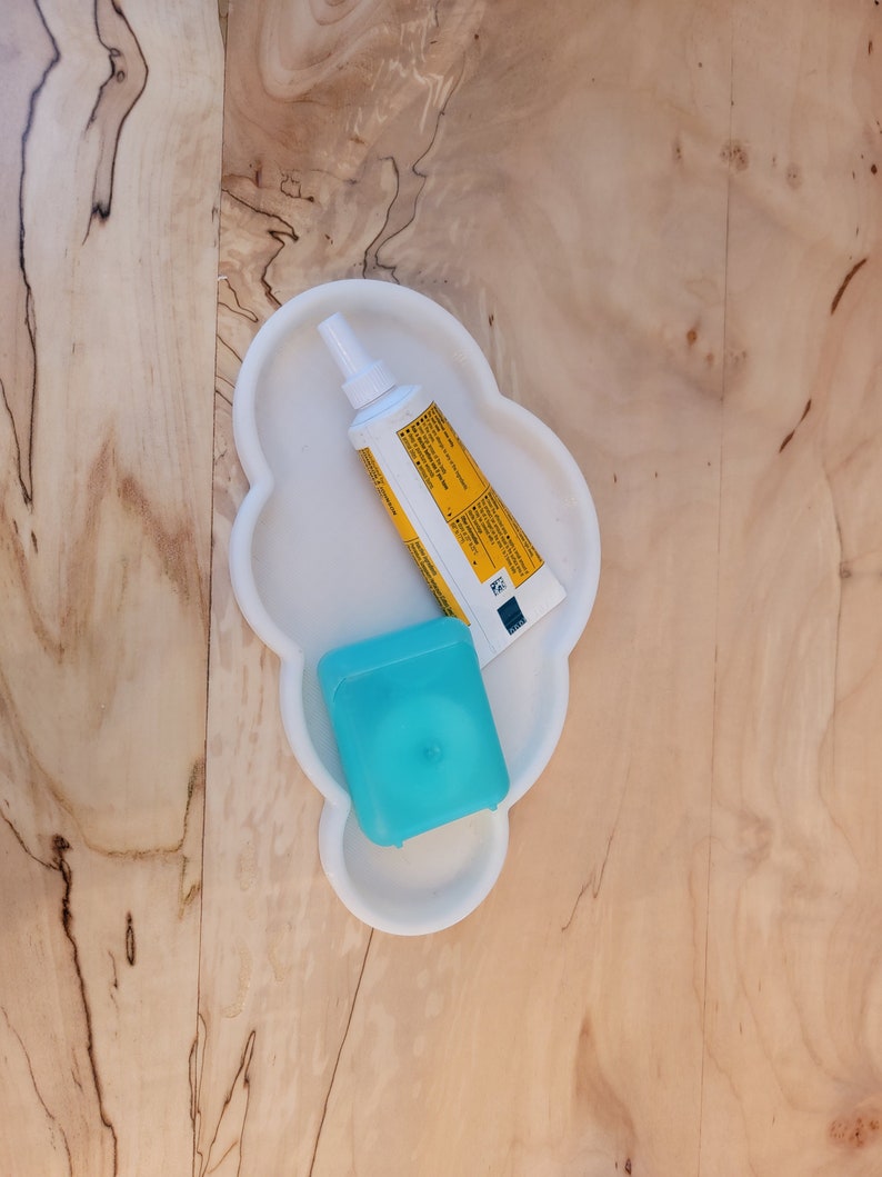 May include: A white cloud-shaped tray with a yellow tube of toothpaste and a blue floss container.
