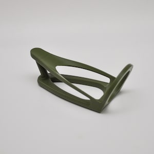 K&ouml;nnte beinhalten: Ein gr&uuml;ner Fahrrad-Wasserflaschenhalter aus Kunststoff. Der Halter ist so konzipiert, dass er an einen Fahrradrahmen passt.