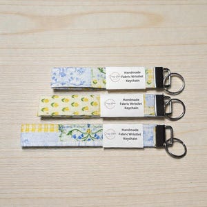 Könnte beinhalten: Ein Set aus drei Keramikbechern mit gesprenkelter, matter Oberfläche. Die Becher sind in Creme-, Hellgrau- und Dunkelgrautönen gehalten. Jeder Becher hat ein schlichtes, minimalistisches Design und einen abgerundeten Henkel.