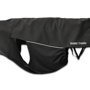 May include: Black dog coat with a white stripe and the text "Double Trouble" on the back.