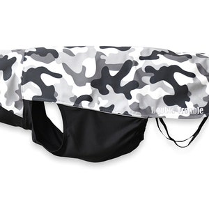 May include: A black and white camouflage dog coat with a black lining and the text "Double Trouble" on the back.