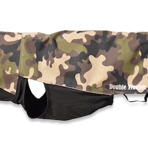 May include: A camouflage dog coat with a black under layer. The coat has the words "Double Trouble" printed on the back.