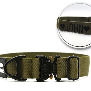 Pode incluir: Coleira para cães verde-oliva com fivela de metal preta e patch de couro preto. A coleira tem o nome "JOHN" impresso com dois corações pretos. O patch diz "Double Trouble" em texto branco.