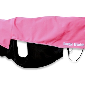 May include: Pink dog coat with black lining and the text "Double Trouble" in white.