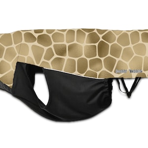 May include: A baby carrier cover with a giraffe print pattern in tan and brown. The cover has a black pouch and the text "Double Trouble" in silver.