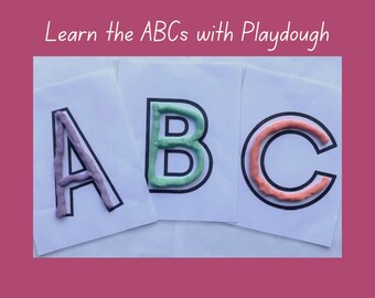 Op de afbeelding: Drie witte kaarten met zwarte contouren van de letters A, B en C. Elke letter is gevuld met Play-Doh in verschillende kleuren: paars, groen en oranje.