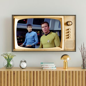 Puede incluir: Un televisor vintage con marco dorado y una pantalla que muestra una escena de la serie de televisión Star Trek. La pantalla muestra dos personajes, uno con un uniforme azul y el otro con un uniforme amarillo.