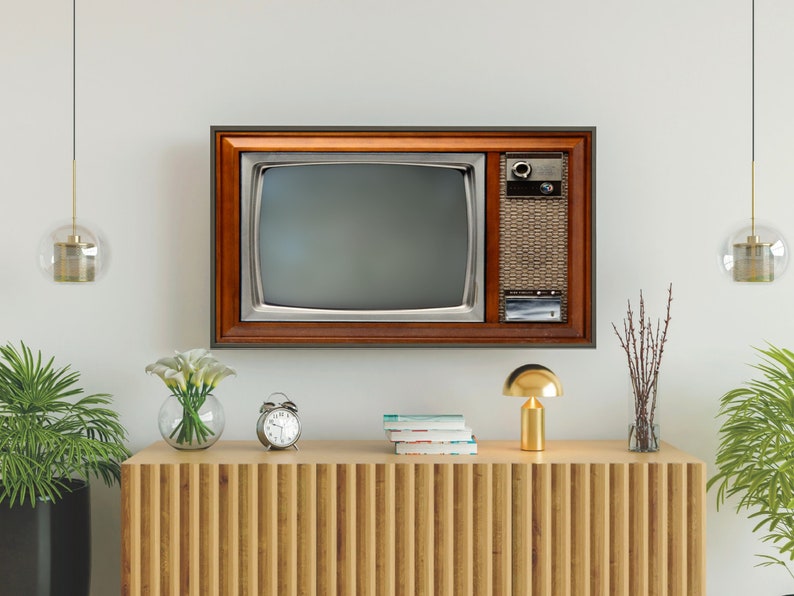 May include: A vintage television set with a wooden frame and a brown cabinet sits on a wooden shelf with a gold lamp and a vase of white flowers.