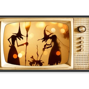 May include: A vintage television set with a black and white screen showing a silhouette of two witches stirring a cauldron. The television is a light beige color with a black frame and a grid pattern on the right side.