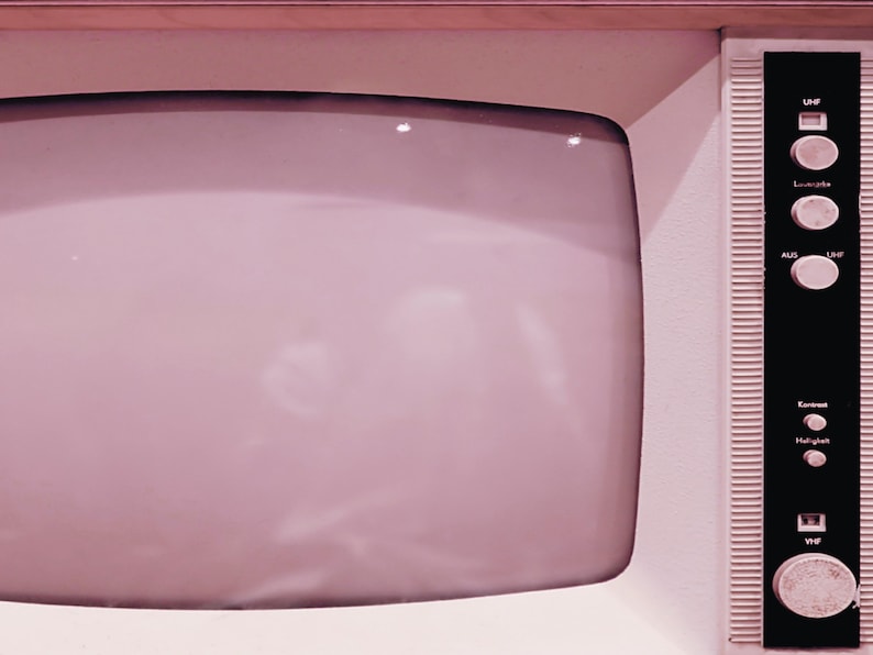 May include: A vintage television with a pink plastic casing and a black control panel with buttons labeled "UHF", "Lucalite", "AUS", "L/MF", "Ext. Ant", "Halligan", and "VHF".