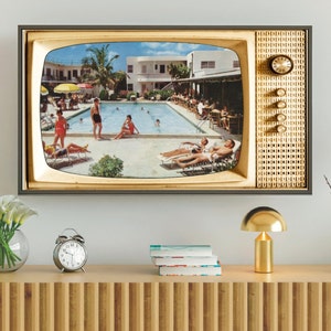 Op de afbeelding: Een ingelijste print met een vintage televisie. Het scherm toont een zonnige zwembadsc&egrave;ne met mensen die ontspannen en zwemmen. De tv-frame is goudkleurig, met een klok en bedieningsknoppen aan de zijkant.