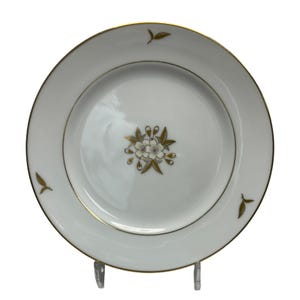 Puede incluir: Plato de porcelana blanca con borde dorado y diseño floral. El plato presenta un arreglo floral central dorado y blanco y detalles de hojas doradas. Una pieza clásica para servir comida.