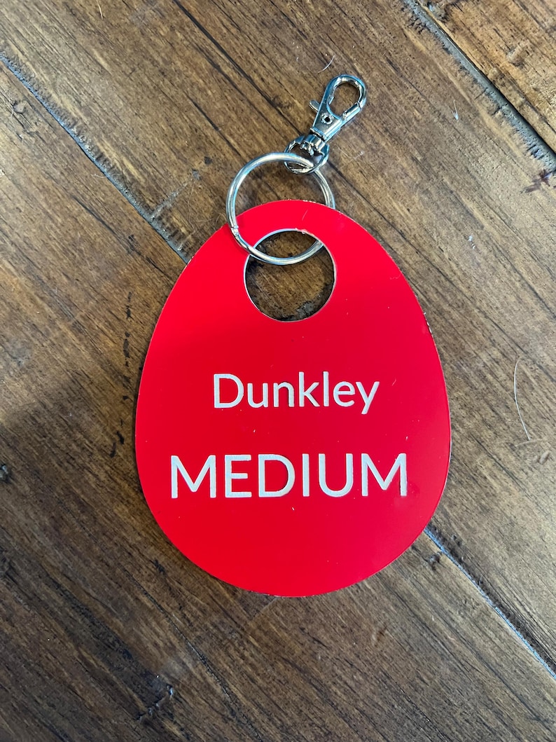 May include: Red oval-shaped key tag with a silver key ring. The tag has the text "Dunkley MEDIUM" printed in white.