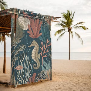 Könnte beinhalten: Dunkelblauer Strandvorhang mit Meereslebewesen-Design. Der Vorhang zeigt ein Seepferdchen, Fische und verschiedene Korallen- und Algenillustrationen in Beige-, Rosa- und Türkistönen. Der Vorhang hängt an einer Holzkonstruktion an einem Sandstrand.