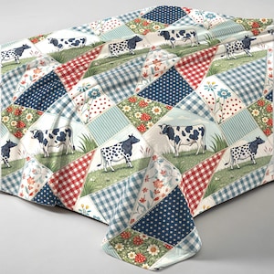Könnte beinhalten: Eine Patchwork-Tischdecke mit einem sich wiederholenden Muster von Kühen auf einer Wiese, durchsetzt mit floralen, gepunkteten und karierten Quadraten. Die Farbpalette umfasst Rot, Blau, Weiß und Grün und erzeugt eine rustikale, ländliche Ästhetik.